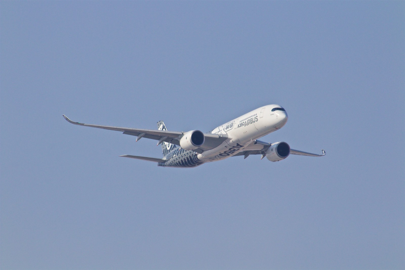 Airbus airplane in clear sky, angled upward in flight.